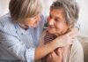 Two older women embracing and smiling on a couch