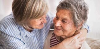 Two older women embracing and smiling on a couch