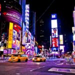Times Square at night with bright billboards and yellow taxis