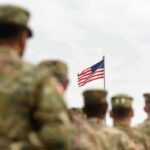 Trusted Recruiter Hijacked Recruits’ Lives U.S. flag flying above a formation of soldiers in uniform