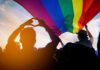 Crowd under a rainbow flag at sunset
