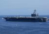 Aircraft carrier at sea with crew lining the deck