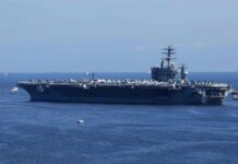 Aircraft carrier at sea with crew lining the deck