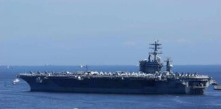 Aircraft carrier at sea with crew lining the deck