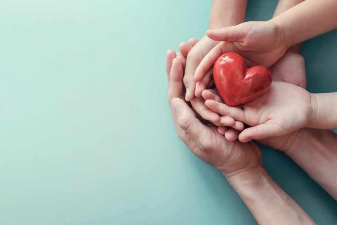 shutterstock_1487364161 Hands holding a red heart