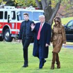 three people walking on grass near fire truck and SUV