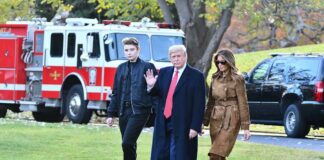 three people walking on grass near fire truck and SUV