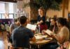 Wage War Collides With Vanishing Paychecks Server taking orders from a group at a restaurant table
