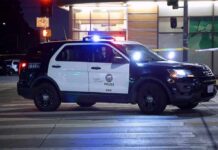 Police SUV blocks an intersection at night with lights flashing