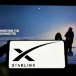 Smartphone showing Starlink logo in front of a computer screen