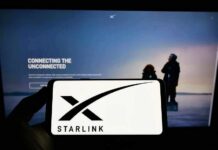 Musk Holds Ukraine’s Trigger Smartphone showing Starlink logo in front of a computer screen