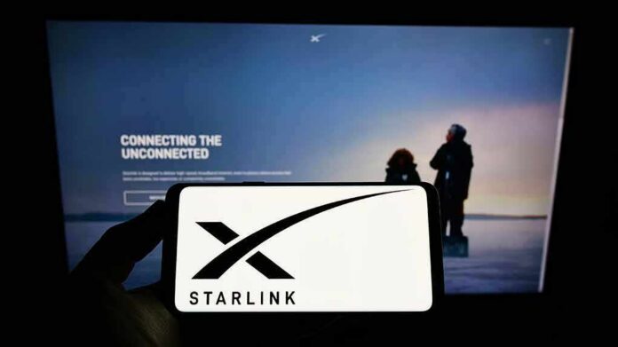 Smartphone showing Starlink logo in front of a computer screen