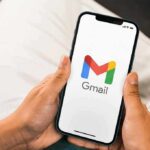 Gmail Lowers the Drawbridge Hands holding a smartphone displaying the Gmail app logo