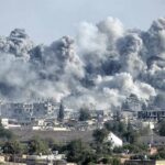 Massive smoke plumes rise over a city after explosions