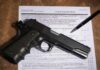 Handgun on a firearms transaction form with a pen