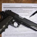 Handgun on a firearms transaction form with a pen