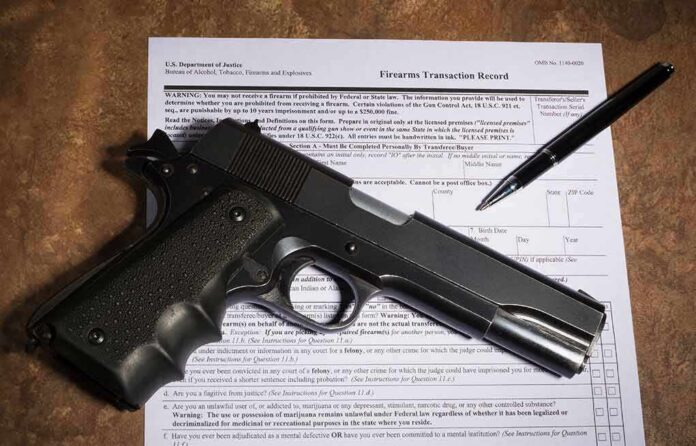 Handgun on a firearms transaction form with a pen