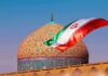 Iranian flag waves before an ornate mosque dome at sunset