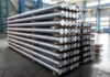 Stacked metal rods on pallets in an industrial warehouse