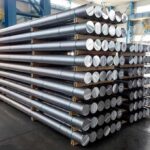 Stacked metal rods on pallets in an industrial warehouse