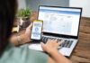 Viral Stair Struggle Triggers Windfall Person using smartphone to approve bank transfer beside laptop with online banking