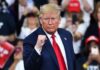 man in suit raising a clenched fist at a rally