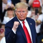 man in suit raising a clenched fist at a rally
