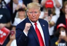 man in suit raising a clenched fist at a rally