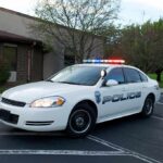 Police car with flashing lights parked outside a building
