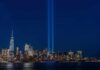 City skyline at night with twin blue light beams rising into the sky