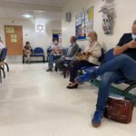 People wearing masks seated in a hospital waiting room