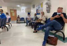 People wearing masks seated in a hospital waiting room