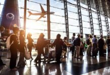 Passengers queue inside an airport terminal at sunset