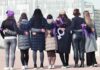 Group of women standing arm in arm with purple ribbons