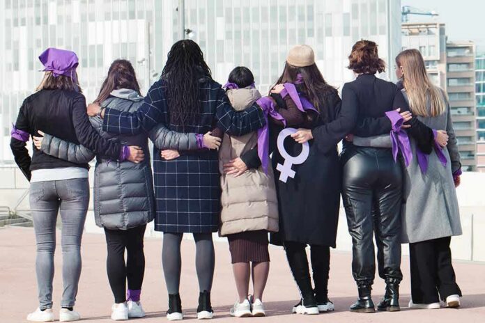Group of women standing arm in arm with purple ribbons