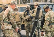 Russia Test Looms: U.S. Brigade Rolls In Soldiers in camouflage gather around a mortar during field training