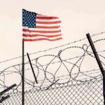American flag above barbed wire fence