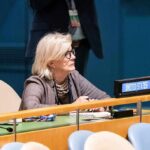 Woman seated at a United Nations desk with a United States nameplate