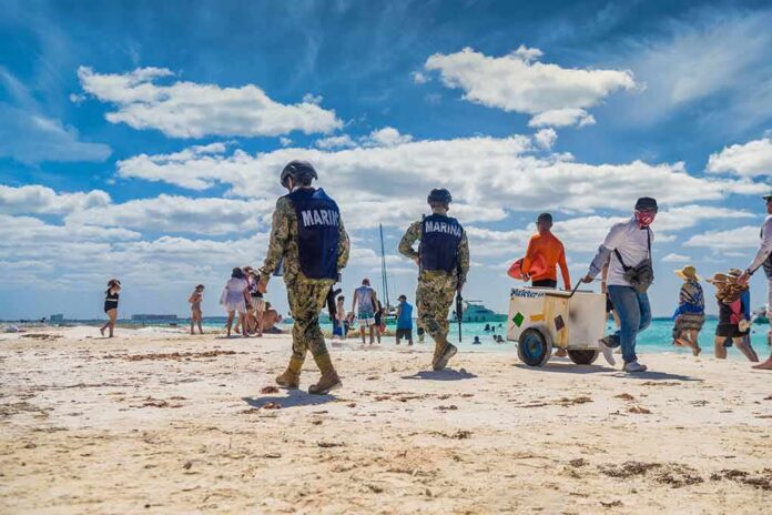 Beach patrol officers walking among beachgoers on a sunny shoreline