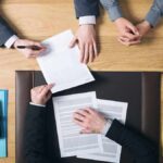 business meeting with hands reviewing and signing documents
