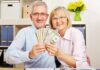Smiling senior couple holding a fan of US dollar bills