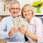 Smiling senior couple holding a fan of US dollar bills