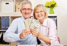Massive Refund Wave—Inflation Time Bomb? Smiling senior couple holding a fan of US dollar bills