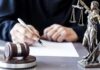 Ex-Mayor Walks After 90 Days Judge writing at desk with gavel and Lady Justice statue