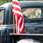 American flag on the bed of a weathered vintage pickup truck