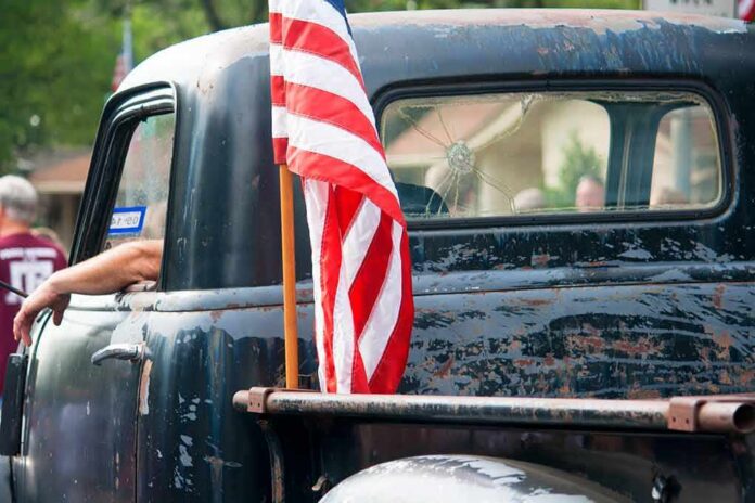 American flag on the bed of a weathered vintage pickup truck