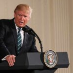 Donald Trump speaking at a podium with presidential seal