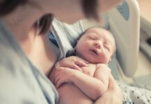 newborn baby sleeping in a parent's arms