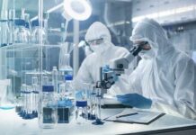 Hospital Warning: Sugar Fuels Superbug Scientists in protective suits using a microscope in a laboratory