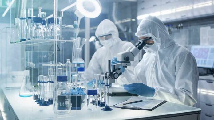 Scientists in protective suits using a microscope in a laboratory